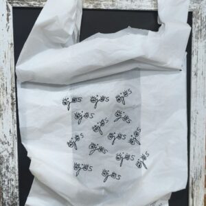Obra Siempre me están observando: ojos bordados sobre una bolsa de plástico blanca, enmarcada sobre fondo negro