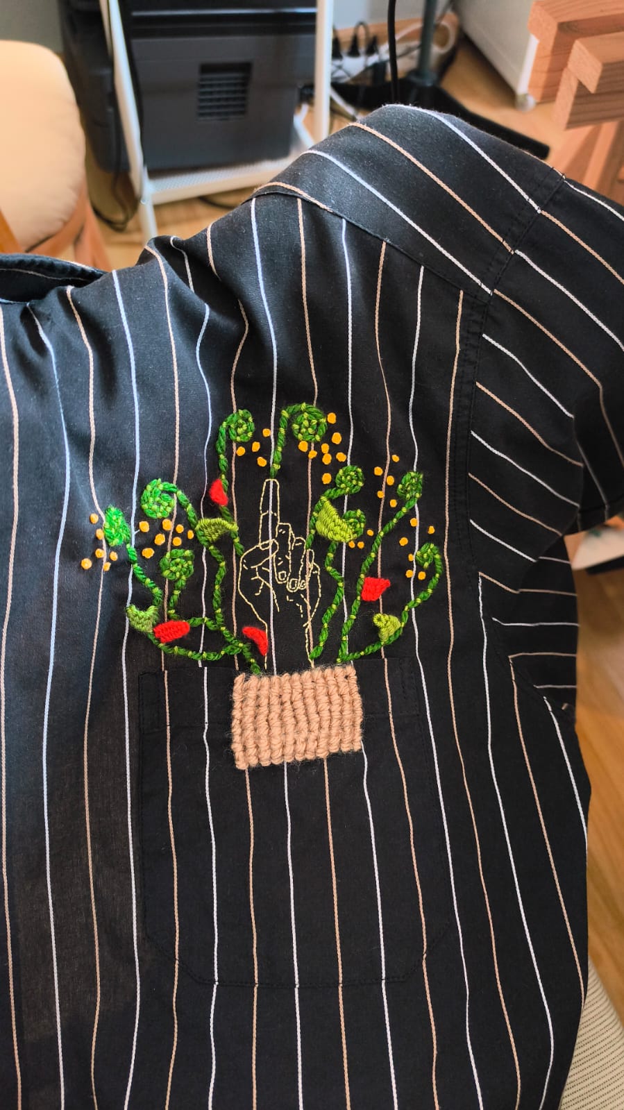 Camisa upcycling bordada, vista completa de la prenda colgada en una percha.